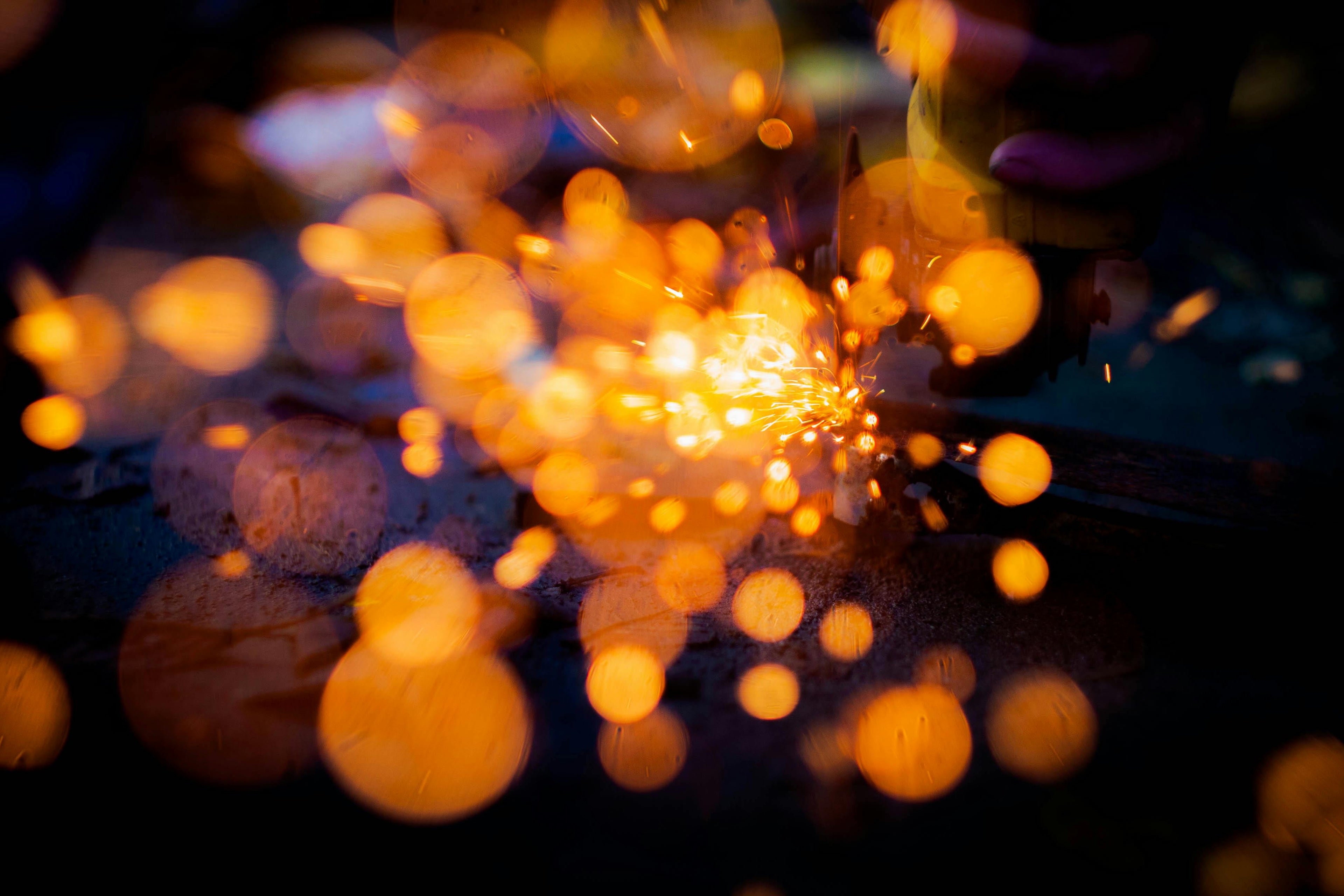 Close-up of glowing yellow sparks against metal